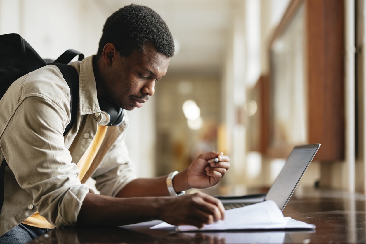 University Student Studying with Laptop in Bright Hallway.