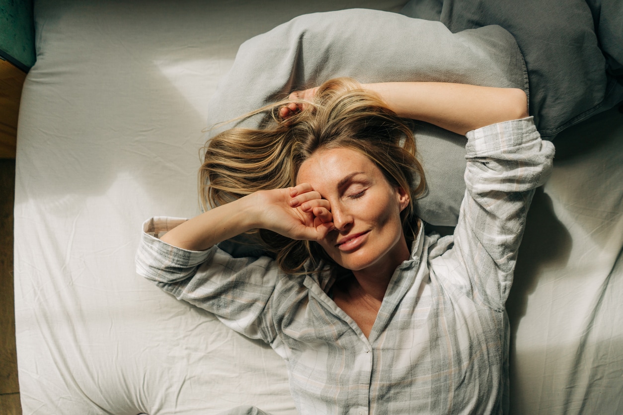 Woman Lies In Bed After Waking Up And Stretches And Rubs Her Eyes