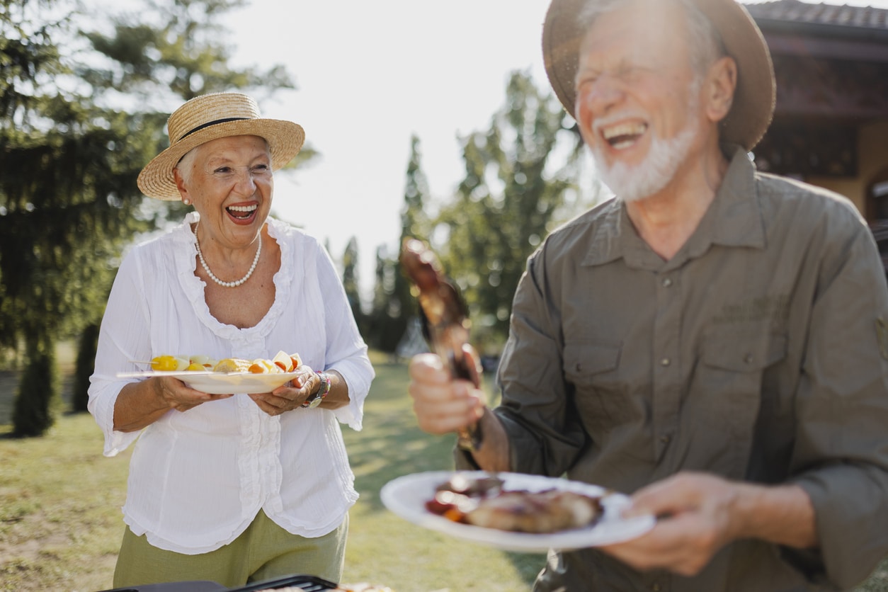 Senior couple standing with their plates of barbecued food.