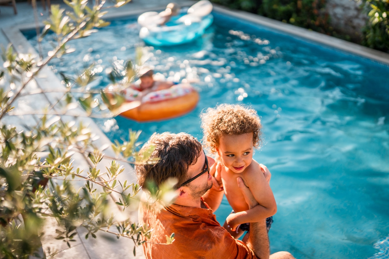 Father and son sitting on the edge of the pool.