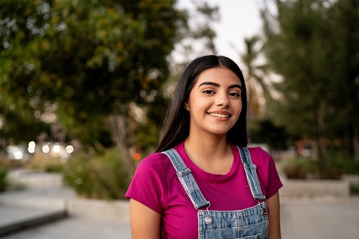 Teen girl smiling and standing in a courtyard.