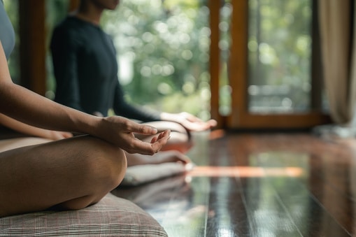 Two people meditating on pillows in a yoga studio.